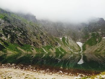 Scenic view of lake by mountains against sky