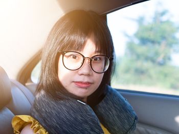 Portrait of young woman wearing eyeglasses sitting in car