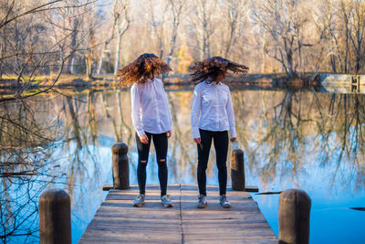 Rear view of women standing by bare trees