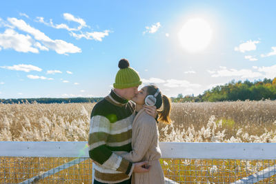 Rear view of man and woman standing on field against sky