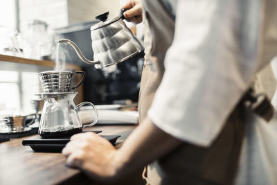 Midsection of man pouring coffee in cup