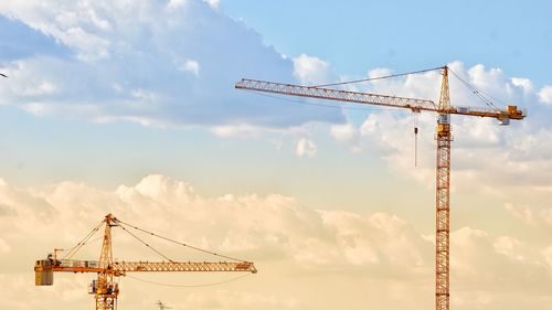 Cranes at construction site against sky