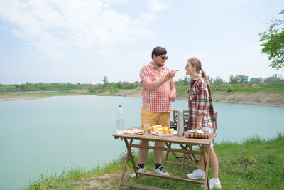 Rear view of woman using mobile phone by lake
