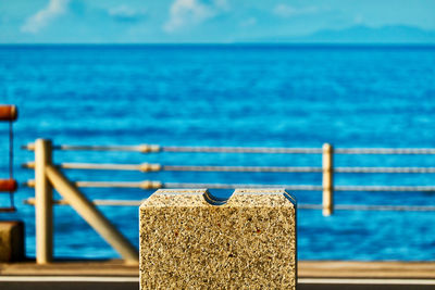 Close-up of wooden post by sea against blue sky