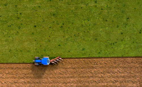 Aerial high angle view of tractor ploughing field