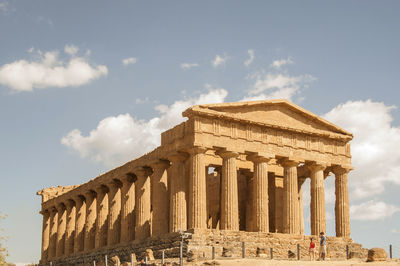 Low angle view of greek temple against cloudy sky