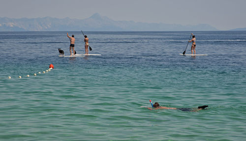 People swimming in sea against sky