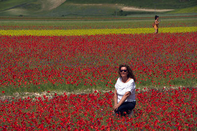 Full length of woman with red flowers on field