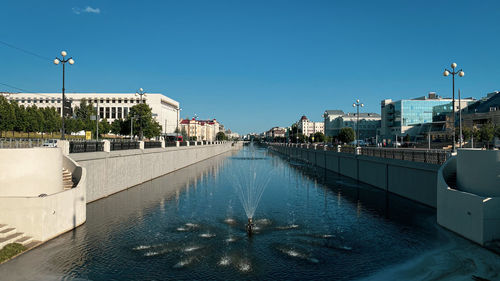 Panoramic view of the drainage canal with water fountain against the background of a sunny sky.