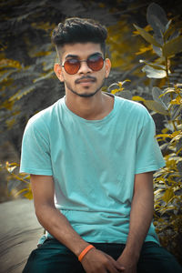 Young man wearing sunglasses sitting outdoors