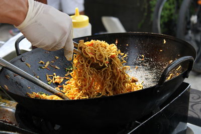 Cropped hand of person preparing noodles