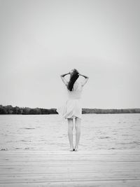 Woman standing by sea against clear sky