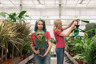 Portrait of female friends standing by plants