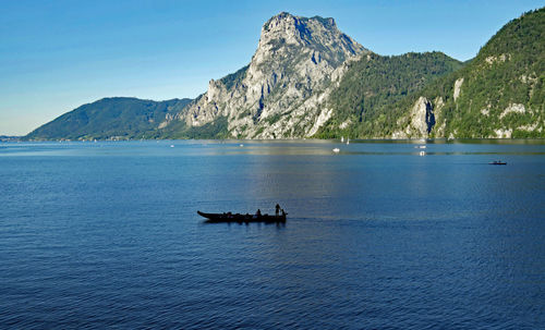 Scenic view of sea and mountains against blue sky