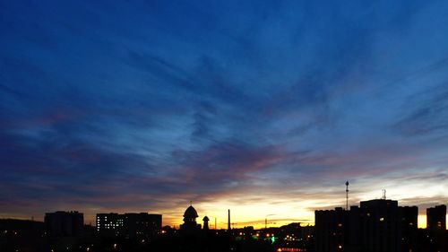 Silhouette buildings in city against sky during sunset