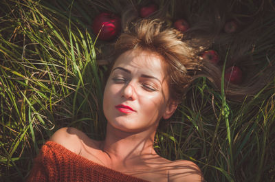Directly above of woman lying with apples on grassy field