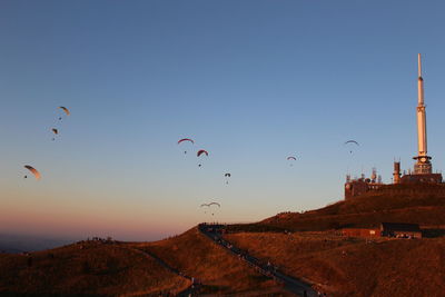 Low angle view of birds flying against clear sky during sunset