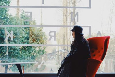 Close-up of woman sitting against window