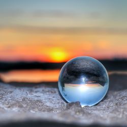 Close-up of crystal ball against sky during sunset