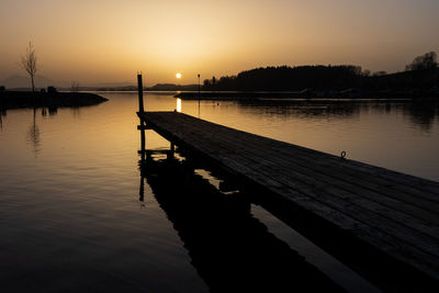 Pier over lake against sky during sunset