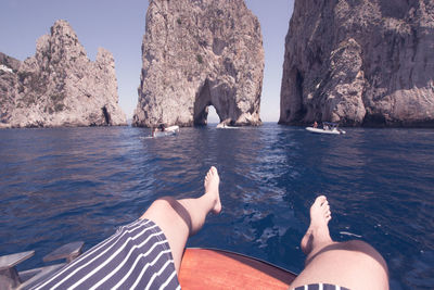 Low section of woman on rock by sea