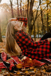 Midsection of woman with autumn leaves in forest