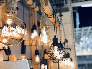 Low angle view of illuminated light bulb hanging from ceiling