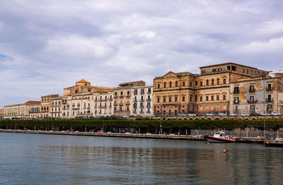 Buildings by river against sky