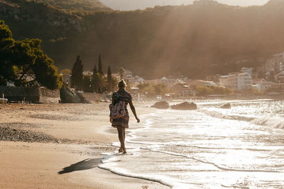 Rear view of woman walking at shore