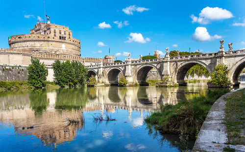 Arch bridge over river against cloudy sky