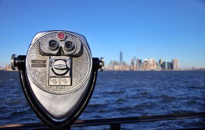 Coin-operated binocular by hudson river against clear blue sky