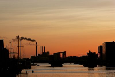 Silhouette bridge over river against sky during sunset