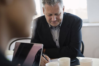 Mature businessman writing during meeting in office