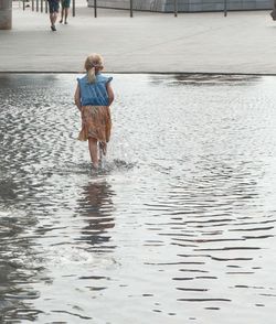 Rear view of boy walking in water