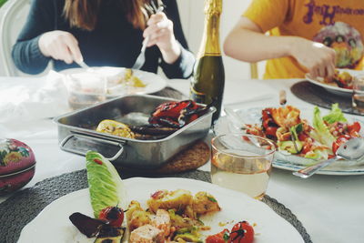 Midsection of people eating meal at table