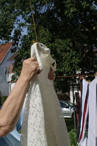 Cropped image of women hanging dress on clothesline while standing in yard