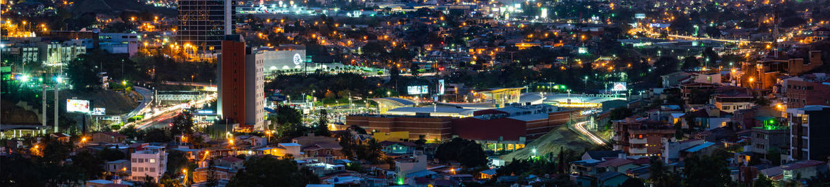 High angle view of illuminated street amidst buildings at night