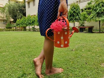 Midsection of woman holding umbrella on field