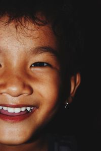Close-up portrait of smiling girl against black background