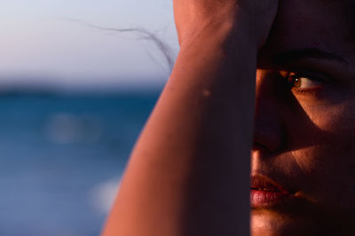 Close-up of thoughtful woman looking away against sea