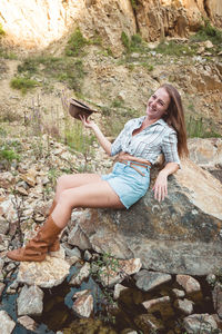 Full length of young woman sitting on rock