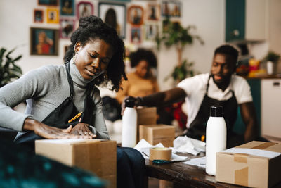 Young female hairdresser labeling box in barber shop