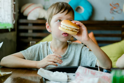 Boy eating a big burger with a cutlet. hamburger in the hands of a child. delicious chicken burger. 