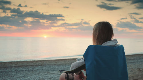 Rear view of woman on beach during sunset