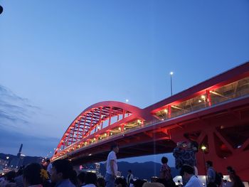 People in illuminated city against sky at dusk