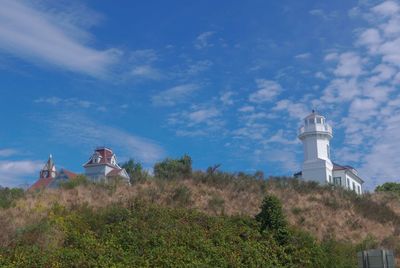 Low angle view of lighthouse by building against sky