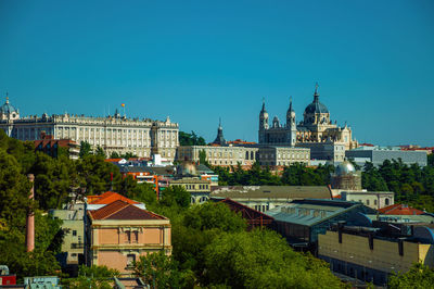 Landscape with the royal palace, almudena cathedral and buildings among leafy trees inmadrid, spain.