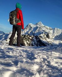 Rear view of person by snowcapped mountain against clear blue sky