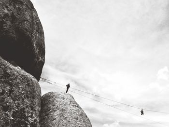 Two people gliding on zip line against the sky