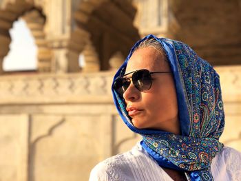 Woman wearing scarf while standing against historic building